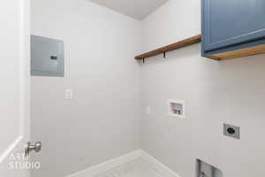 Washroom with electric panel, hookup for an electric dryer, washer hookup, cabinet space, and light tile patterned floors