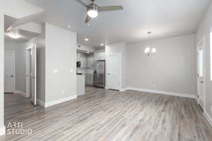 Unfurnished living room with a chandelier, light wood-style floors, ceiling fan, and recessed lighting