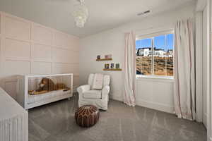 Bedroom featuring a decorative wall, carpet, a chandelier, and a crib