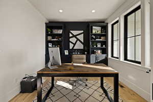 Office space with light wood finished floors, recessed lighting, and built in shelves