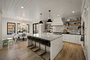 Kitchen with white cabinetry, open shelves, decorative light fixtures, a breakfast bar area, and decorative backsplash
