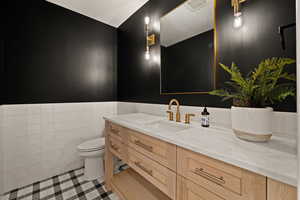 Bathroom with vanity, wainscoting, a textured ceiling, and light tile patterned floors