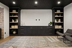 Bar area featuring built in features, dark cabinets, open shelves, recessed lighting, and light wood-style flooring