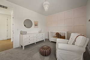 Sitting room featuring carpet and a decorative wall