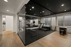 Workout room with light wood-type flooring and recessed lighting
