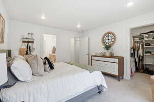 Carpeted bedroom featuring a walk in closet, recessed lighting, and ensuite bathroom