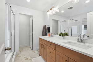 Full bath featuring a stall shower, light marble finish flooring, double vanity, and recessed lighting