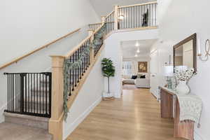 Stairway with wood finished floors and a towering ceiling
