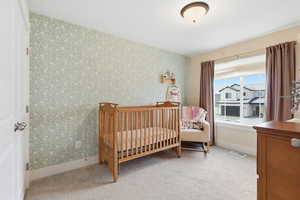 Carpeted bedroom with wallpapered walls and a crib