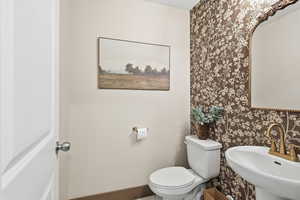 Half bath with wallpapered walls and toilet