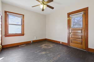 Empty room with dark wood-type flooring and a ceiling fan
