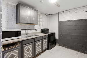 Kitchen featuring black electric range oven, gray cabinetry, white microwave, and light countertops