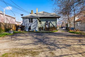 Rear view of house with a chimney and roof with shingles