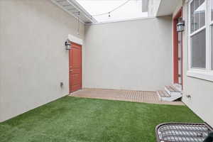 Entrance to property with stucco siding and a lawn