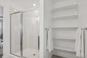 Full bathroom with a stall shower, recessed lighting, and a closet