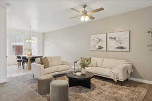 Carpeted living room with a ceiling fan and a chandelier