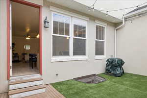 Entrance to property featuring stucco siding, a wooden deck, and a lawn