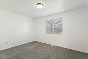 Empty room with dark carpet and baseboards