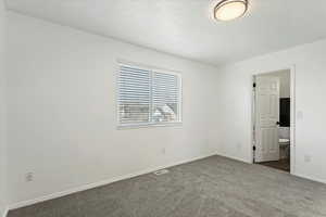 Empty room featuring dark colored carpet and baseboards