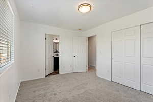 Unfurnished bedroom with carpet, a closet, and ensuite bath