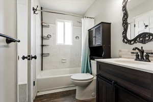 Bathroom with vanity, shower / tub combo with curtain, and dark wood finished floors