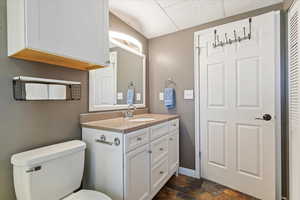 Half bathroom featuring vanity, a paneled ceiling, stone finish floors, and a closet