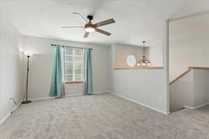 Carpeted spare room with a chandelier and ceiling fan