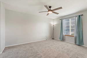 Carpeted empty room featuring ceiling fan and baseboards