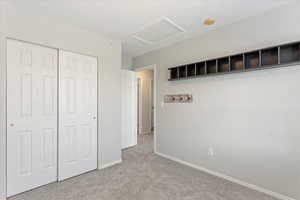Unfurnished bedroom with attic access, a closet, and carpet flooring