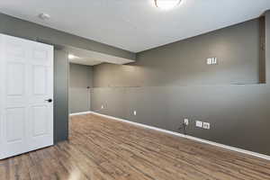 Empty room featuring wood finished floors and a textured ceiling