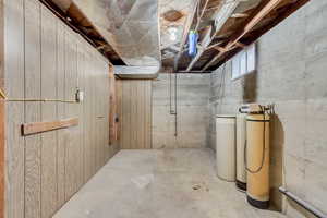 Below grade area featuring a water softener and wooden walls