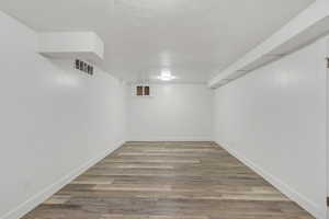 Finished basement with light wood-type flooring and a textured ceiling