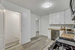 Kitchen featuring wood counters, white cabinetry, stainless steel appliances, and light wood-type flooring
