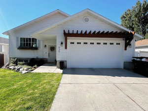View of front of property with an attached garage, driveway, and a front yard