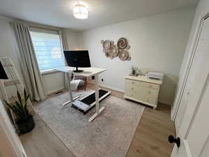 Home office with light wood finished floors and baseboards