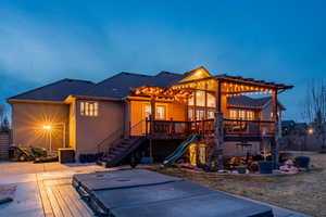 Back of property featuring stairs, a deck, an outdoor hot tub, and roof with shingles