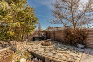 Fenced backyard featuring a patio area and a fire pit