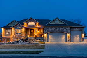 View of front of property with stone siding, driveway, an attached garage, and a porch