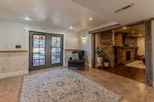 Living area featuring a textured ceiling, french doors, a fireplace, and recessed lighting
