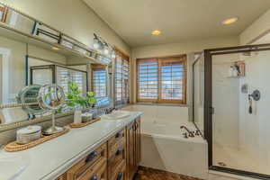 Full bathroom with a bath, a stall shower, a textured ceiling, and double vanity