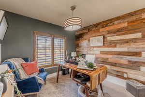Office space with wood walls, carpet flooring, and an accent wall