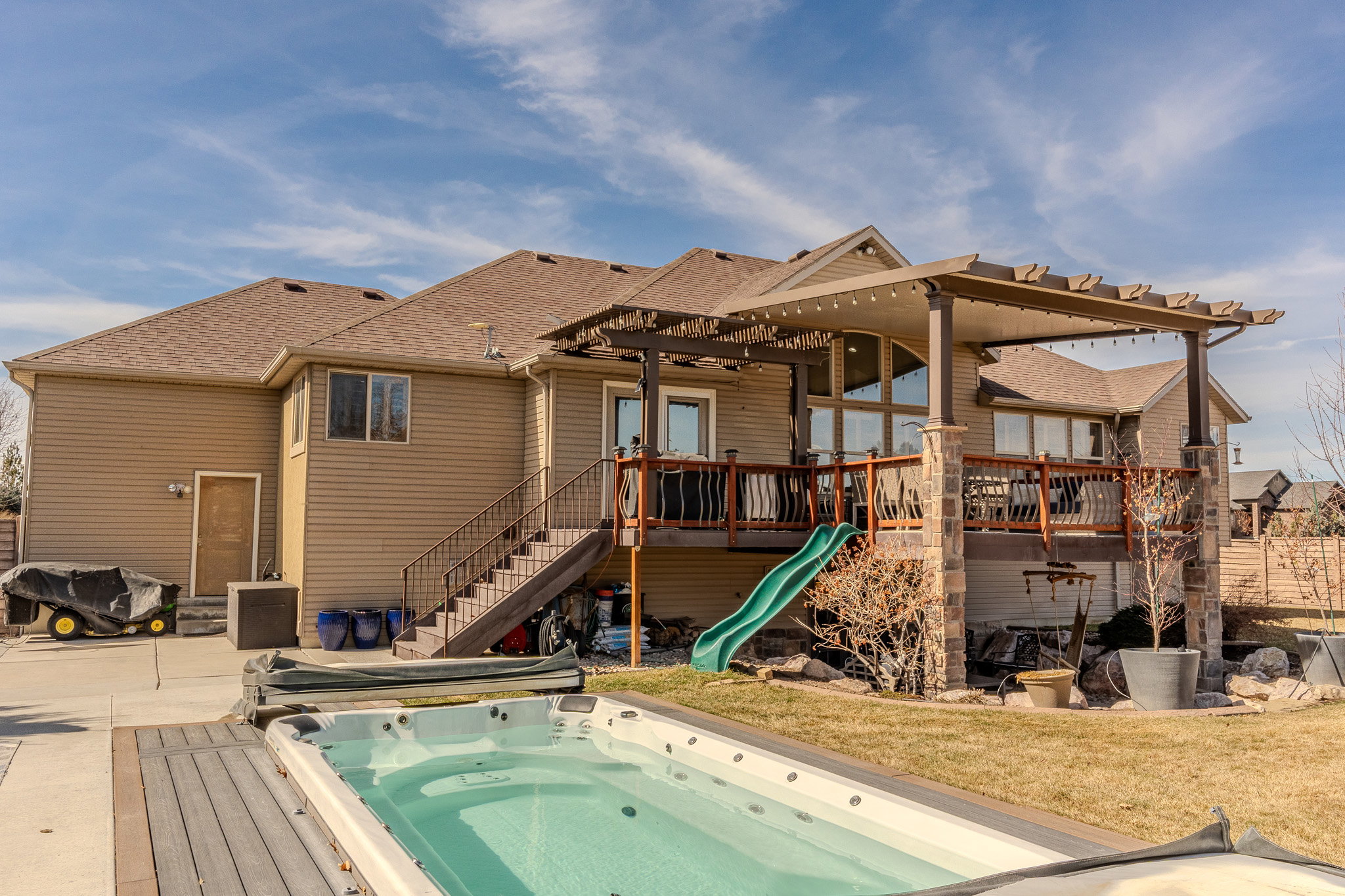 View of pool with stairs, a wooden deck, a pergola, a yard, and a patio