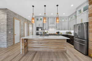 Chefs Kitchen with upgraded lighting, cabinets, wood accents and oversized waterfall granite island