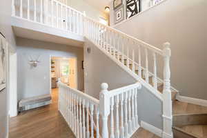 Stairs with a towering ceiling and wood-type flooring