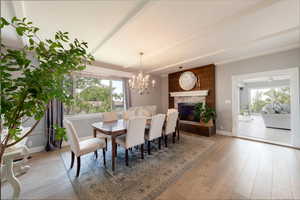 Dining room featuring light wood-style flooring, a chandelier, and a fireplace