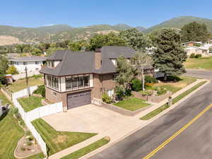 View of front facade featuring a mountain view, a chimney, driveway, stucco siding, and a residential view