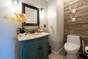 Half bathroom with vanity, wood walls, and light tile patterned floors