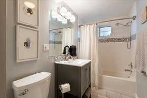 Full bathroom featuring shower / tub combo with curtain, vanity, and light tile patterned floors