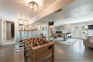 Rec room with ornamental molding, billiards, a textured ceiling, and finished concrete flooring