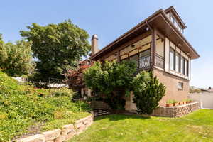 View of side of home featuring brick siding, a chimney, and a balcony
